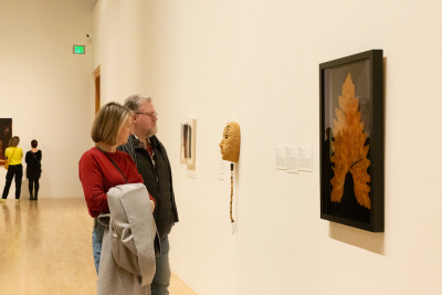 two people looking at a large leaf with photographic images of people 
